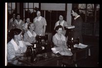 Group of women at sewing machines. Black and white photo. 